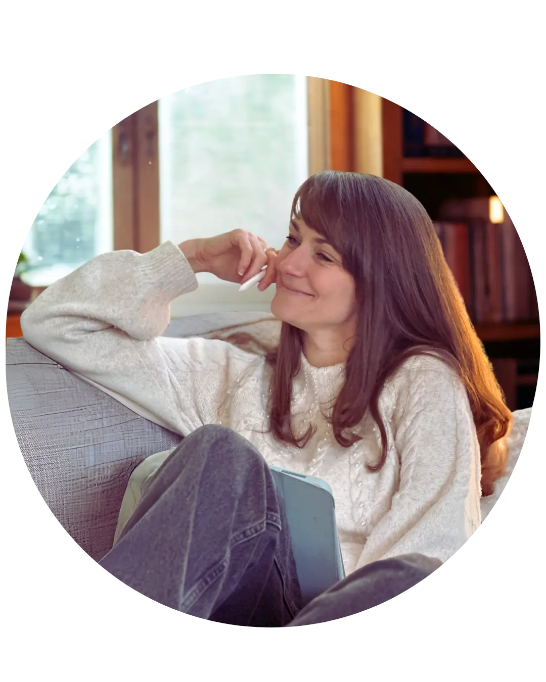 Judith Ring sitzt auf einem Sofa. Sie lächelt einem Gesprächspartner zu, der außerhalb der Kamera sitz. Hinter ihr ein Fenster und ein Regal mit Büchern.