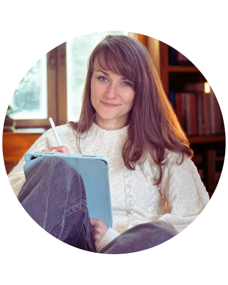 Judith Ring sitzt auf einem Sofa. Sie lächelt in die Kamera. Hinter ihr ein Fenster und ein Regal mit Büchern.