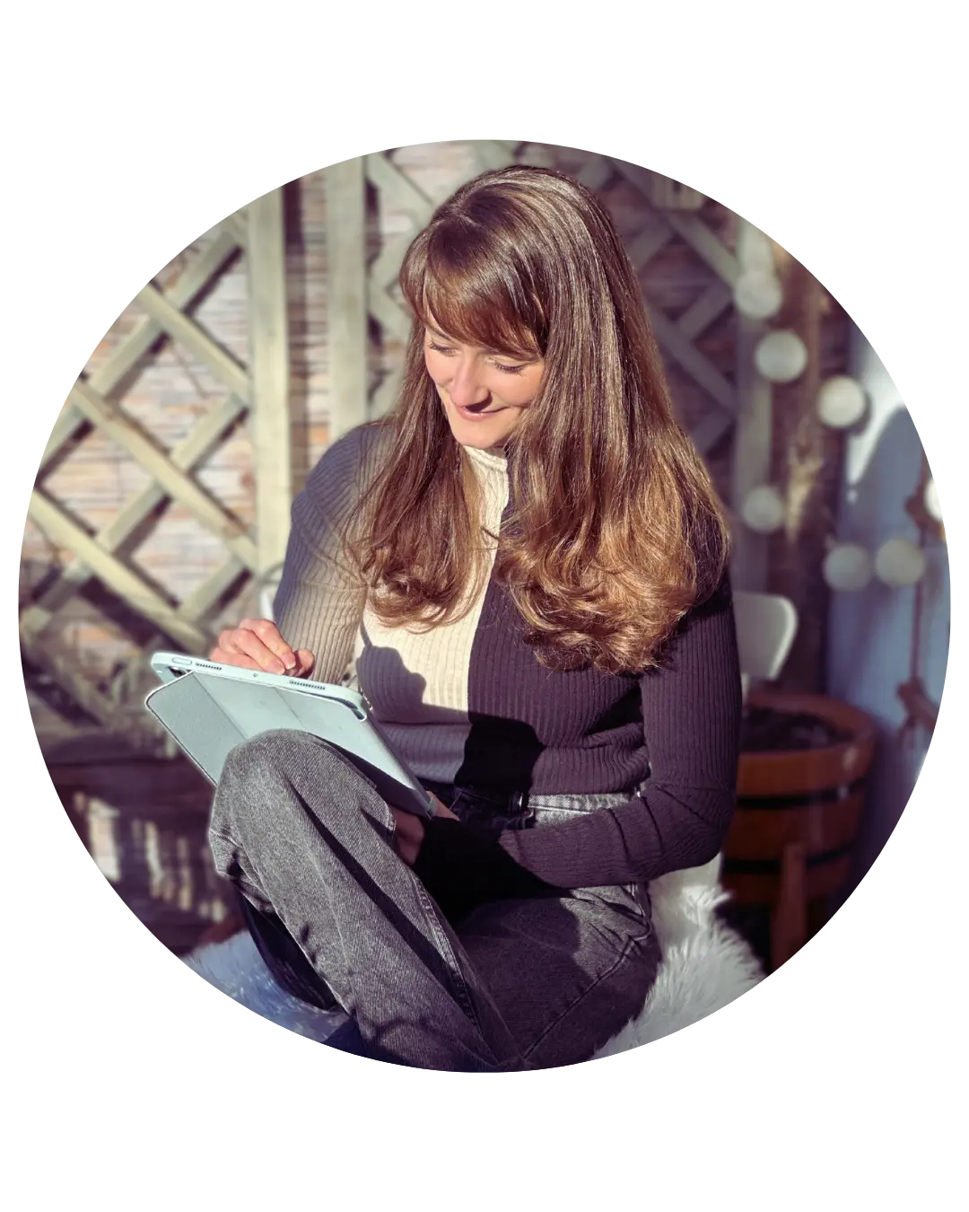 Judith Ring sitzt in der Sonne auf dem Balkon und schreibt lächelnd in ihr Schreibheft.